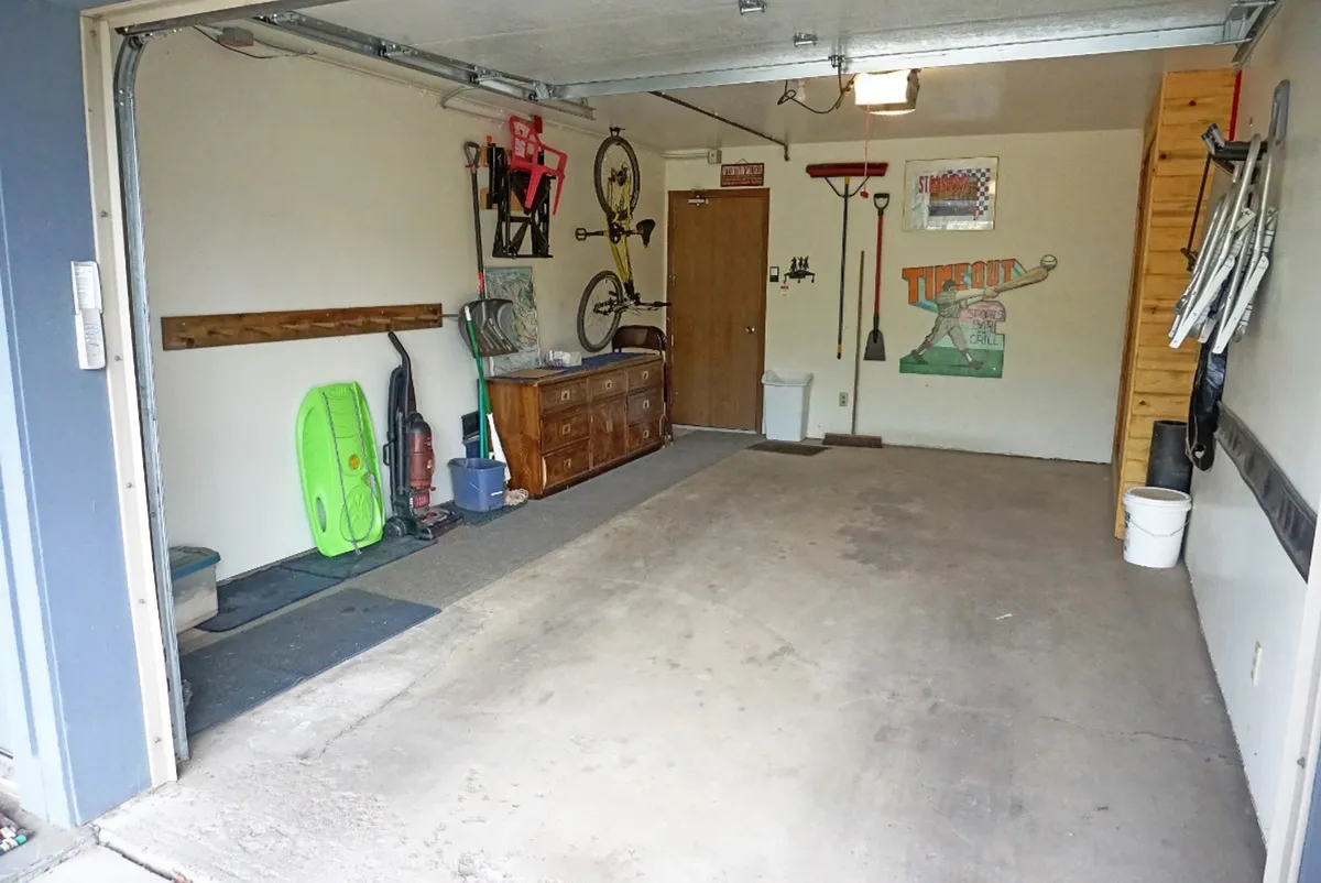 This image captures a practical storage area with a bicycle, sports equipment, a dressing table, and colorful wall art. The presence of the bike and other gear emphasizes the space's suitability for organizing and prepping equipment for outdoor adventures.