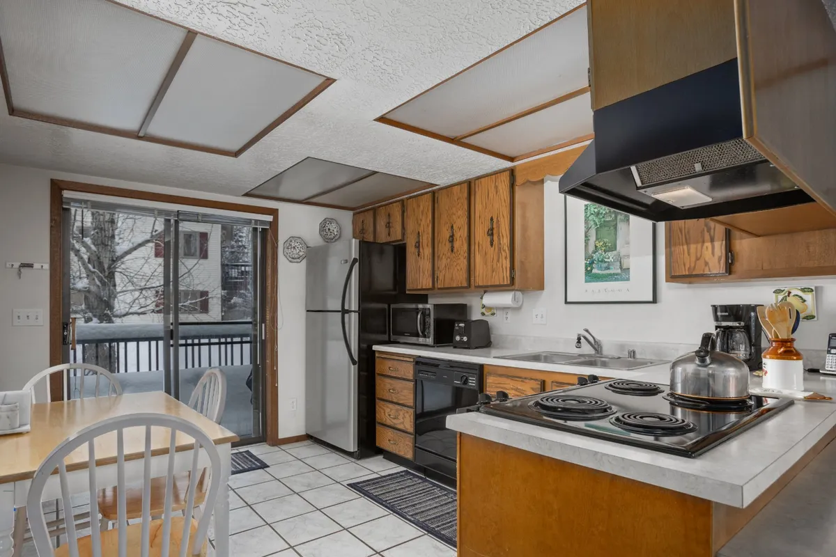 A view of the open-concept dining and kitchen area featuring a kitchen island, a large dining table, and a generous window offering views outside. The space is designed for hosting meals, celebrations, and family gatherings, with warm lighting and welcoming decor.