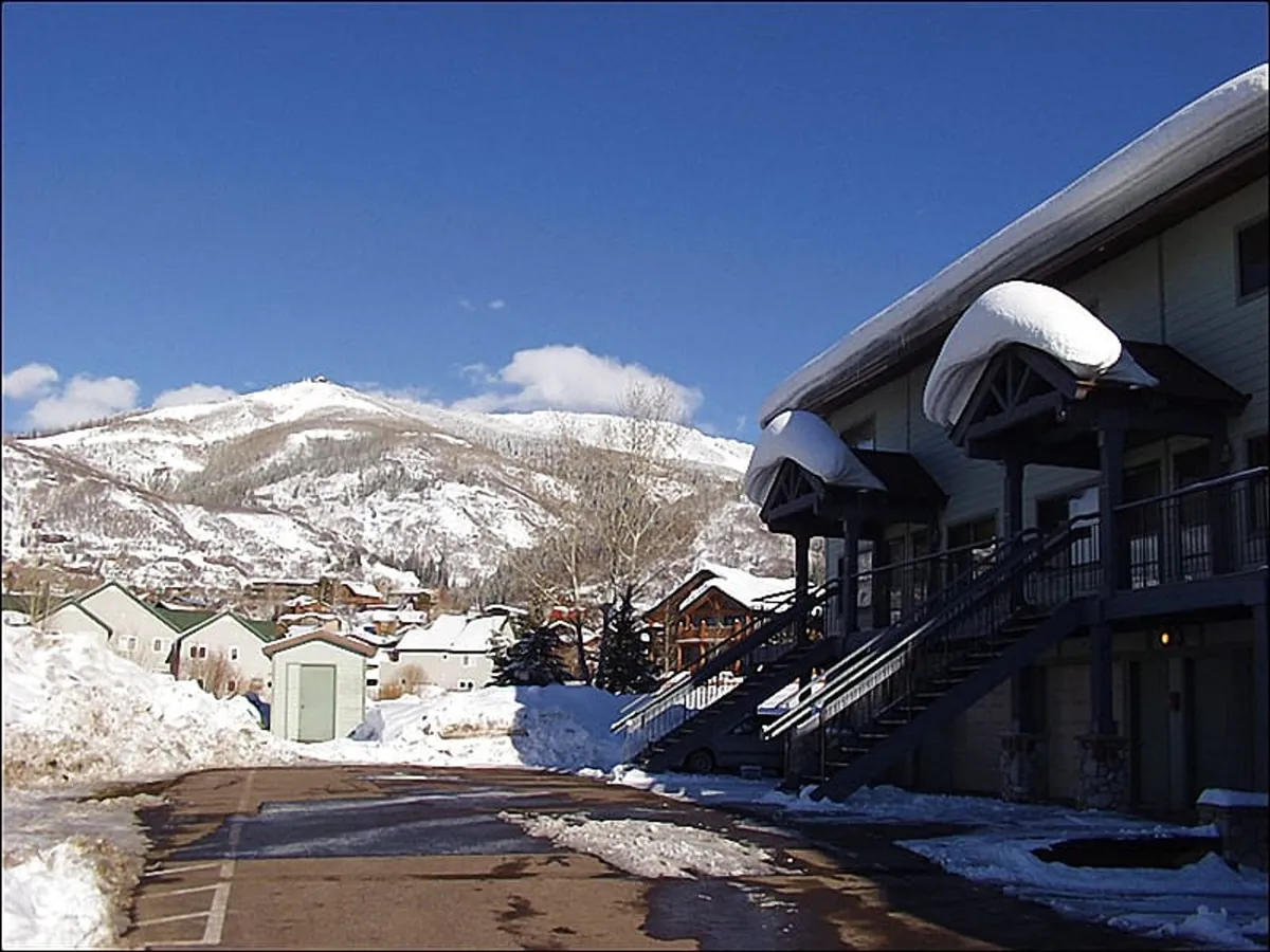 This image features a snow-covered mountain landscape with a prominent building facade and stairs leading up, set against a tranquil winter backdrop. The snow hints at abundant opportunities for skiing and snowboarding, while the building is evocative of convenient slope-side accommodations.