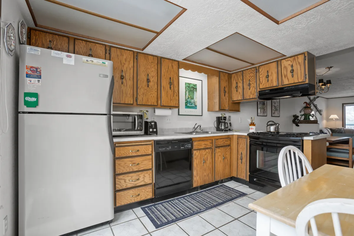This image depicts a cozy kitchen featuring wooden cabinets, stainless steel appliances, and a dining table set nearby. Decorative wall art adds a homey touch, while the ample workspace and modern appliances cater to family cooking and entertaining.