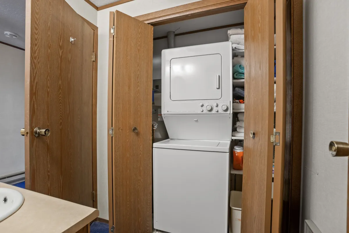 A laundry area featuring a washer and dryer unit, stacked towels, and wooden doors, conveying a sense of practical organization and readiness for cleaning up after outdoor activities.